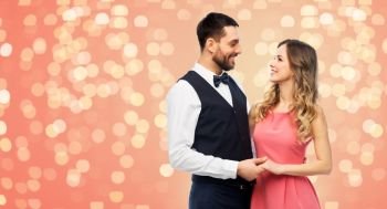 people concept - happy couple in party clothes over living coral background and festive lights. happy couple in party clothes