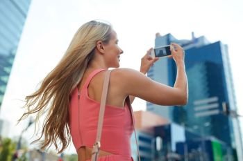 women and people concept - happy smiling young woman with smartphone photographing city. young woman with smartphone photographing city