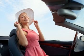 travel, road trip and people concept - happy young woman wearing sun hat in convertible car. happy young woman in convertible car