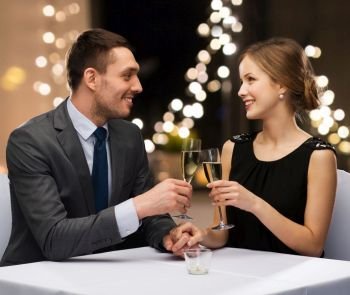 dating, celebration and valentines day concept - smiling young couple clinking glasses of non-alcoholic champagne and looking at each other over festive lights on background. couple with glasses of champagne at restaurant