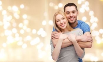 love, relationships and people concept - smiling couple hugging over beige background with festive lights. smiling couple hugging over festive lights
