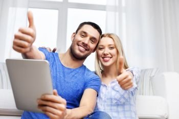 technology, internet and people concept - happy couple with tablet computer showing thumbs up at home. couple with tablet computer showing thumbs up