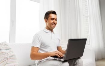 technology, people and internet concept - happy man with laptop computer at home. happy man with laptop computer at home