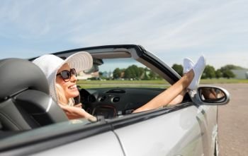 transport, leisure and people concept - happy woman in summer hat and sunglasses chilling in cabriolet car outdoors. happy woman driving in cabriolet car
