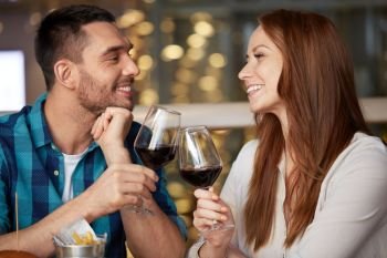 celebration, holidays and people concept - happy couple drinking red wine at restaurant. happy couple drinking red wine at restaurant