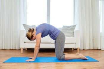 fitness, yoga and healthy lifestyle concept - woman doing cat pose on mats at home. woman doing yoga cat pose at home