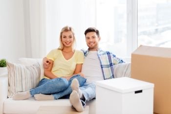 mortgage, moving and real estate concept - happy couple with boxes resting on sofa at new home. happy couple with boxes moving to new home