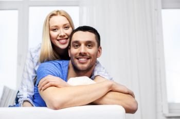 relationships and people concept - happy couple sitting on sofa and hugging at home. happy couple sitting on sofa and hugging at home