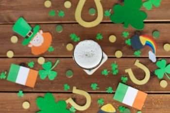 st patricks day, holidays and celebration concept - glass of draft beer and party props on wooden table top view. glass of beer and st patricks day party props