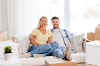 mortgage, moving and real estate concept - happy couple with boxes resting on sofa at new home. happy couple with boxes moving to new home