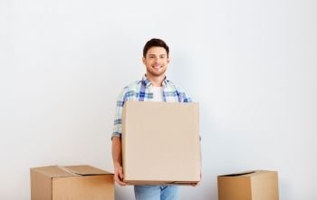 moving, people and real estate concept - happy man holding cardboard box at new home. happy man with cardboard box moving to new home