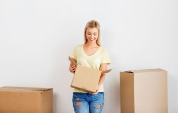 moving, people and real estate concept - happy man holding cardboard box at new home. happy woman with cardboard box moving to new home