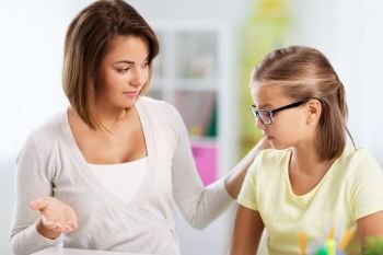 education, family and learning concept - displeased mother talking to daughter while doing homework at home. upset mother talking to daughter doing homework