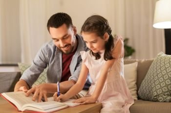 education, family and homework concept - happy father and daughter with book writing to notebook at home. father and daughter doing homework together