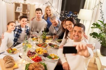 celebration, holidays and people concept - happy family having dinner party at home and taking selfie by smartphone. family having dinner party and taking selfie