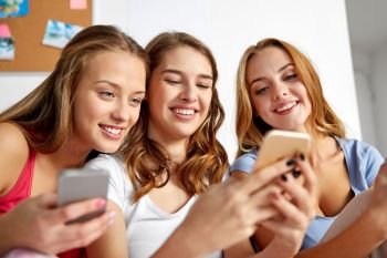 friendship, pajama party and technology concept - happy friends or teenage girls with smartphones at home. friends or teen girls with smartphones at home