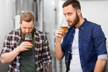 alcohol production, manufacture, business and people concept - men drinking and testing craft beer at brewery. men drinking and testing craft beer at brewery