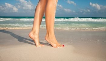 summer vacation and pedicure concept - closeup of woman legs walking on exotic beach sand. closeup of woman legs walking on beach sand
