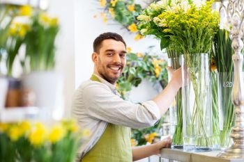 small business, sale and floristry concept - happy florist man setting flowers at flower shop. happy florist man setting flowers at flower shop