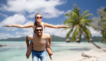 travel, tourism and people concept - happy couple having fun in summer over tropical beach background in french polynesia. happy couple having fun in summer