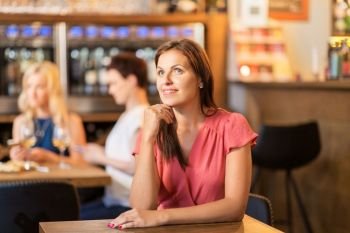 people and lifestyle concept - happy middle aged woman at wine bar or restaurant. happy middle aged woman at wine bar or restaurant