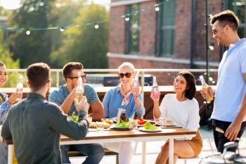 leisure and people concept - happy friends with non alcoholic drinks having barbecue party on rooftop. happy friends with drinks or bbq party on rooftop