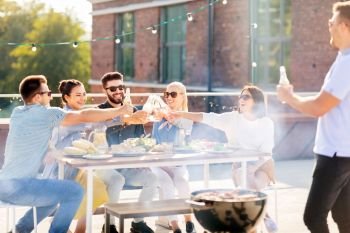 leisure and people concept - happy friends toasting non alcoholic drinks at bbq party on rooftop in summer. friends toast drinks at bbq party on rooftop