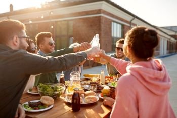 leisure and people concept - happy friends toasting drinks at rooftop party or picnic in summer. happy friends toasting drinks at rooftop party