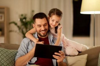 family, fatherhood and technology concept - happy father and little daughter with tablet pc computer at home in evening. father and daughter with tablet computer at home