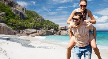 travel, tourism and people concept - happy couple having fun over tropical beach on seychelles island background. happy couple having fun seychelles island