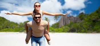 travel, tourism and people concept - happy couple having fun over tropical beach on seychelles island background. happy couple having fun on seychelles island