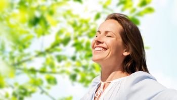 people and leisure concept - happy smiling woman enjoying sun over green natural background. happy woman over green natural background