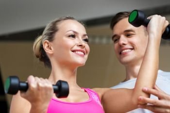 sport, fitness and people concept - smiling woman with personal trainer with dumbbells exercising in gym. woman with dumbbells exercising in gym