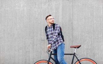 travel, tourism and lifestyle - happy young hipster man in earphones with fixed gear bike and backpack on city street. hipster man with fixed gear bike and backpack