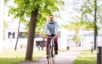 people, style and lifestyle - happy young hipster man riding fixed gear bike on city street. happy young hipster man riding fixed gear bike