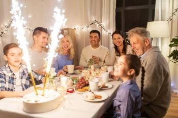 celebration, birthday and people concept - happy family having dinner party with fountain fireworks or sparkler candles burning on cake at home. happy family having dinner party at home