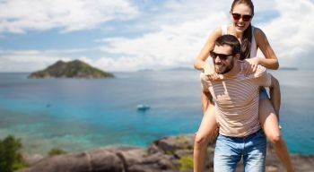 travel, tourism and people concept - happy couple having fun over tropical beach on seychelles island background. happy couple having fun seychelles island
