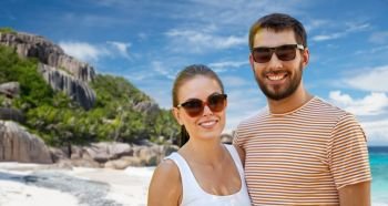 travel, tourism and people concept - happy couple in sunglasses outdoors over tropical beach on seychelles island background. happy couple in sunglasses on seychelles island