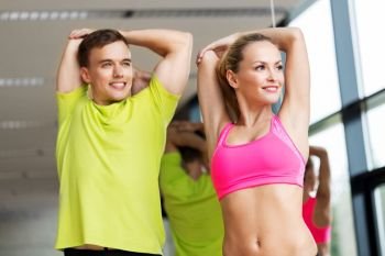 sport, fitness, healthy lifestyle and people concept - smiling man and woman stretching in gym. smiling man and woman exercising in gym