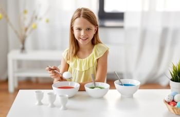 easter, holidays and people concept - happy girl coloring eggs by liquid dye at home. girl coloring easter eggs by liquid dye at home
