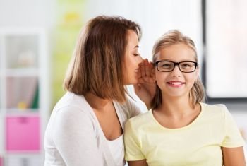trust, gossiping and family concept - happy mother whispering secret to daughter at home. happy mother whispering secret to daughter at home