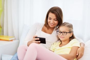 people, family and technology concept - happy mother and daughter with smartphone at home. happy mother and daughter with smartphone at home