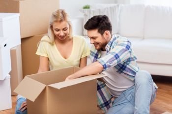 mortgage, moving and real estate concept - happy couple unpacking boxes at new home. happy couple unpacking boxes at new home