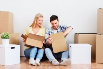 mortgage, moving and real estate concept - happy couple unpacking boxes at new home. happy couple unpacking boxes at new home