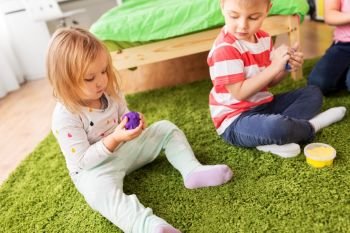 childhood, leisure and people concept - children playing with modelling clay or slimes at home. children with modelling clay or slimes at home