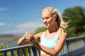 sport, people, technology and healthy lifestyle concept - smiling young woman with fitness tracker exercising outdoors. happy woman with fitness tracker exercising