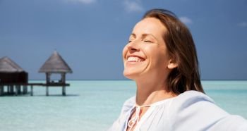 travel, tourism and summer vacation concept - happy smiling woman over exotic tropical beach and bungalow shed background. happy woman over beach and bungalow on background
