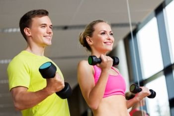 sport, fitness and people concept - couple with dumbbells exercising in gym. couple with dumbbells exercising in gym