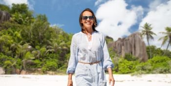 people and summer concept - happy smiling woman walking along over seychelles island tropical beach background. happy woman over seychelles island tropical beach