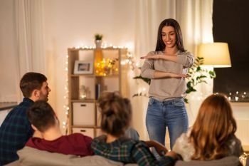 friendship, leisure and entertainment concept - happy friends playing charades game at home in evening. happy friends playing charades at home in evening